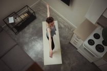Женщина, выполняющая упражнения йоги на кухне дома — стоковое фото