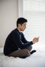Чоловік використовує мобільний телефон на ліжку вдома — стокове фото