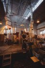 Soffiatore di vetro che lavora sul tavolo del marver alla fabbrica di soffiaggio del vetro — Foto stock