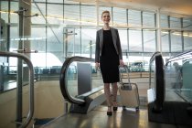 Businesswoman near escalator with luggage at airport — Stock Photo
