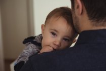 Close-up of father holding baby son at home — Stock Photo