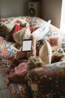 Жінка лежить і використовує цифровий планшет на дивані у вітальні вдома — стокове фото