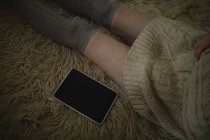 Женщина сидит на полу с цифровым планшетом дома — стоковое фото
