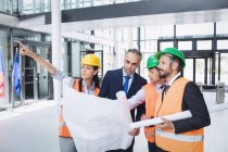 Businessman discussing on blueprint with architects in office building — Stock Photo