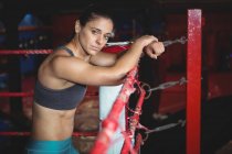 Selbstbewusste Boxerin lehnt im Fitnessstudio am Boxring — Stockfoto