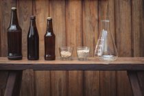 Garrafas de cerveja caseiras e ingredientes com um frasco cônico para cervejaria caseira — Fotografia de Stock