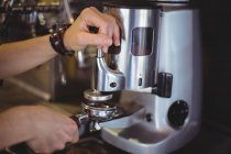Garçonete segurando portafilter preenchido com café moído no café — Fotografia de Stock