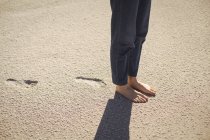 Baixa seção de uma mulher de pé na areia da praia — Fotografia de Stock