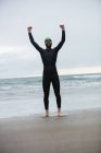 Porträt eines Sportlers, der mit erhobenen Händen am Strand schreit — Stockfoto