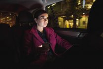 Задумчивая деловая женщина с цифровым планшетом и телефоном в машине — стоковое фото