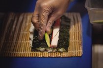 Primer plano de la mano del chef preparando sushi en el restaurante - foto de stock