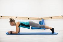 Woman performing stretching exercise in fitness studio — Stock Photo