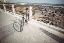 Bicycle leaning by promenade railing near sea shore — Stock Photo