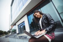 Щаслива жінка використовує ноутбук за межами офісної будівлі — стокове фото