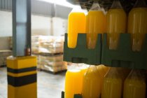 Gros plan des bouteilles de jus jaune disposées dans la caisse à l'entrepôt — Photo de stock