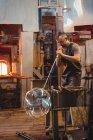 Стеклодувка, формирующая стекло на трубе стеклодувного завода — стоковое фото