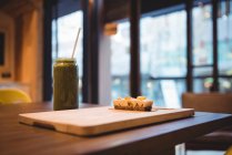 Зеленый фруктовый сок и сладкий десерт на столе в кафе — стоковое фото