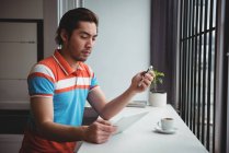 Mann benutzt Handy und digitales Tablet mit Kaffeetasse auf Tisch im Café — Stockfoto