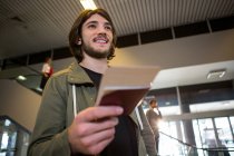 Hombre feliz recibiendo pasaporte y tarjeta de embarque en la terminal del aeropuerto - foto de stock