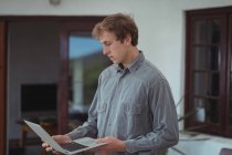 Чоловік стоїть вдома і дивиться на ноутбук — стокове фото