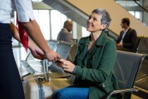 Mujer que da pasaporte a la zona de espera de facturación de aerolíneas en el aeropuerto - foto de stock