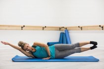 Woman performing stretching exercise in gym — Stock Photo