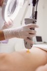 Close-up de médico realizando depilação a laser na pele da coxa do paciente na clínica — Fotografia de Stock