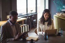 Бизнесмен и коллега с помощью цифрового планшета и ноутбука в офисе — стоковое фото