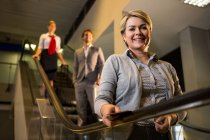 Бізнес-леді з посадковим талоном стоїть на ескалаторі в аеропорту — стокове фото