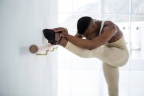 Ballerino s'étirant sur une barre tout en pratiquant la danse de ballet en studio — Photo de stock