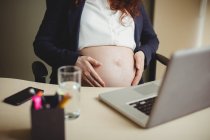 Mid section of businesswoman holding belly in office — Stock Photo