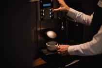 Hands of waiter making cup of coffee from espresso machine in bar — Stock Photo