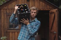 Retrato de un hombre llevando una botella de cerveza en una caja de cerveza casera - foto de stock