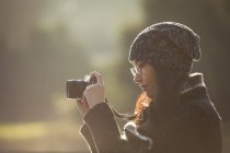 Жінка фотографує цифрову камеру в сонячний день у парку — стокове фото