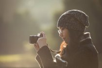 Mujer tomando fotos en cámara digital en un día soleado en el parque - foto de stock