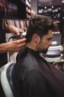 Мужчина стрижется парикмахером с триммером в парикмахерской — стоковое фото