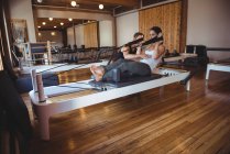 Trainer assisting a woman while practicing pilates in fitness studio — Stock Photo