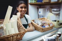 Personal femenino sonriendo en el mostrador de alimentos en el supermercado - foto de stock