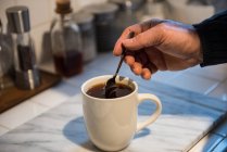Homem preparando um café preto na cozinha em casa — Fotografia de Stock
