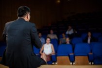 Вид ззаду керівника чоловічого бізнесу, який розмовляє з колегами в конференц-центрі — стокове фото