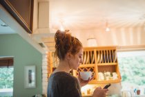 Mulher bonita usando telefone celular na cozinha em casa — Fotografia de Stock