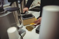Hands of man straining coffee from portafilter — Stock Photo