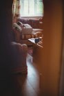 Красива жінка лежить на дивані і використовує ноутбук у вітальні вдома — стокове фото