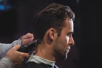 Cliente ottenere capelli tagliati con trimmer in negozio di barbiere — Foto stock