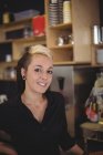 Портрет улыбающейся официантки, стоящей с руками на бедрах в кафе — стоковое фото