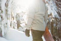 Mid section of woman standing and holding a snowboard on snow covered mountain — Stock Photo