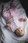 Nahaufnahme eines niedlichen Babys, das zu Hause auf einem Bettlaken liegt — Stockfoto