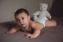 Carino bambino sdraiato sulla pancia in camera da letto a casa — Foto stock
