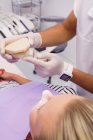Dentista mostrando modelo de prótese para paciente na clínica — Fotografia de Stock