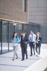 Gruppe selbstbewusster Geschäftsleute geht vor Bürogebäude — Stockfoto